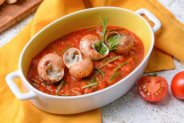 Baking dish with tasty snails on light background