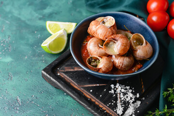 Bowl with tasty snails on color background