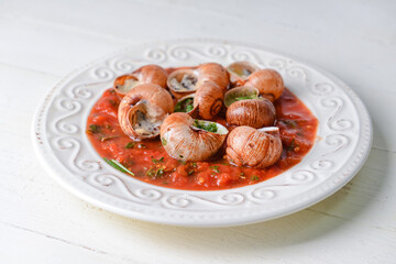 Plate with tasty snails on light background