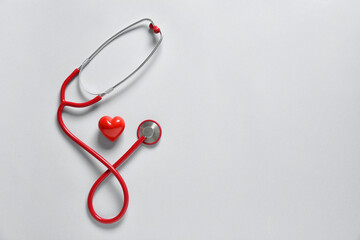 Modern stethoscope and heart on light background