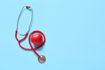 Modern stethoscope and heart on color background