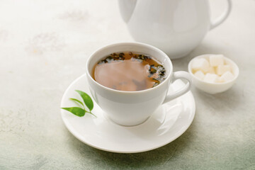 Cup and teapot of green tea on light background