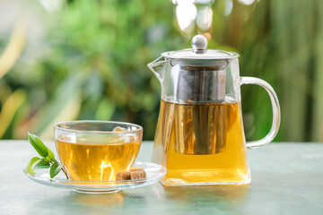 Teapot and cup of hot tea on table outdoors