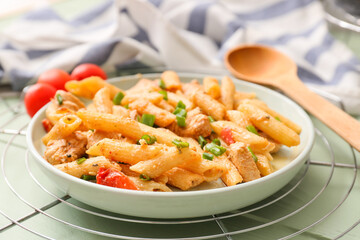 Plate with cajun chicken pasta on color wooden background