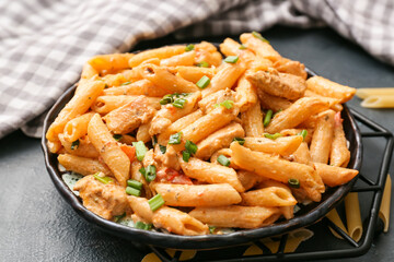Plate with cajun chicken pasta on dark background, closeup