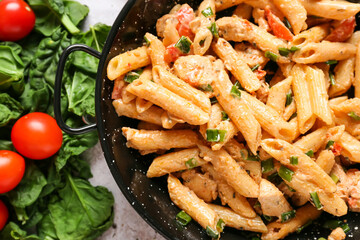 Frying pan with tasty cajun chicken pasta on light background, closeup