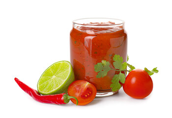 Glass jar of tasty salsa sauce with ingredients on white background