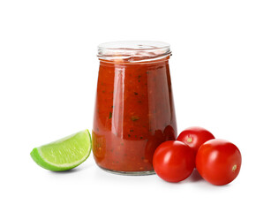 Glass jar of tasty salsa sauce with ingredients on white background