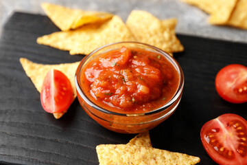 Bowl of tasty salsa sauce with nachos on dark wooden background - obrazy, fototapety, plakaty