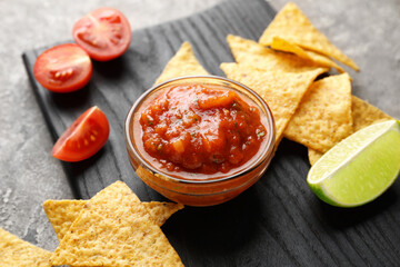 Bowl of tasty salsa sauce with nachos on grunge background