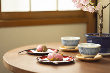 ちゃぶ台に置かれた桜餅と緑茶と桜の花