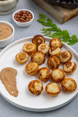 Suji appe or appam served on a appam pan with peanuts and tamarind chutney