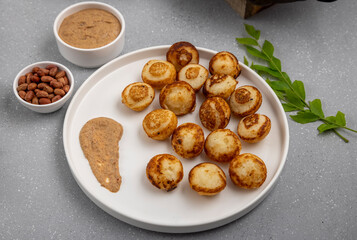 Suji appe or appam served on a appam pan with peanuts and tamarind chutney