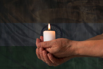 Hands hold a candle against the background of the flag of India. The concept of mourning and sadness in the country, terrorism.
