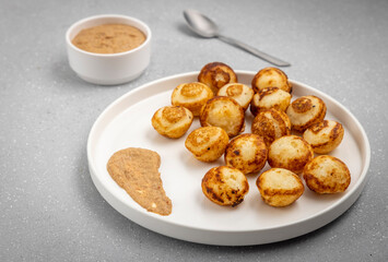 Suji appe or appam served on a appam pan with peanuts and tamarind chutney