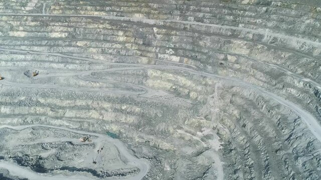Aerial view of explosion in Huge asbestos quarry. Inside the quarry there is a excavators and serpentine road for trucks. In the center of the shot is a site loaded with explosives.
