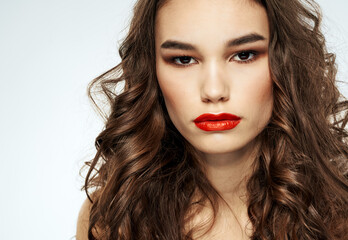 Fototapeta premium Portrait of a beautiful woman with red lips and curly hair at the barbershop
