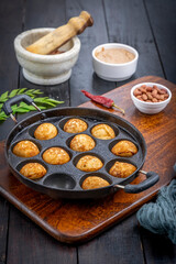 Suji appe or appam served on a appam pan with peanuts and tamarind chutney