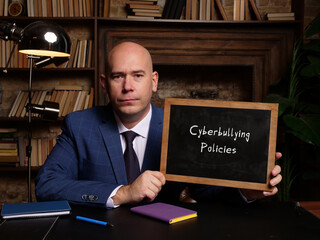 Financial concept about Cyberbullying Policies with sign on chalkboard in hand.
