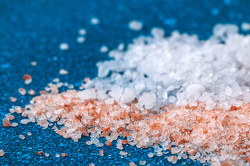 Pink coarse salt crystals on a blue table. Himalaya salt. Background for advertising salty.