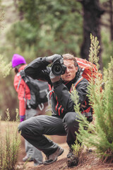 Photographer man taking pictures with professional camera of wildlife animals in nature. Hiker hiking on travel adventure in forest using gear to shoot in the wild.