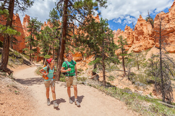 People hiking - couple hikers in Bryce Canyon walking on trail happy with backpacks. Multiracial...
