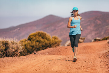 Running sports athlete woman trail runner wearing cap shoes leggings exercising in summer heat....