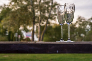 Closeup of two champagne glasses with sand in them, left at a picnic area