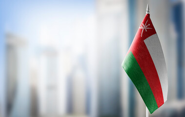 A small flag of Oman on the background of a blurred background