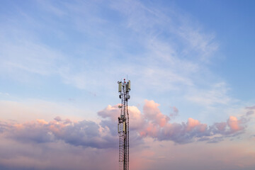 A cell phone tower rises against a twilight sky, a telecommunications tower
