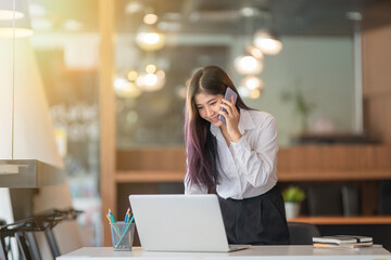 Portrait of businesswoman talking on the phone while working at a worktable in an office room.