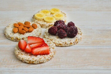 cereal breakfast crisp breads with strawberries, almonds nuts, banana fruit and blackberries on wooden textured table with copy space text