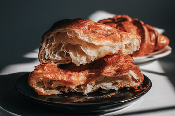 Croissants on a dark background in the morning light, sunlight shadow. Morning breakfast concept. Copy space.