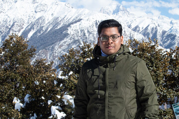 Stylish male hiker standing in front of snowcapped Himalayan mountain