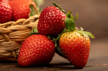 Fresh red strawberries in a wicker basket on a wooden table. Harvesting.