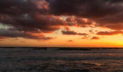 Naklejka na ściany i meble Cloudy sunset at the stormy sea.