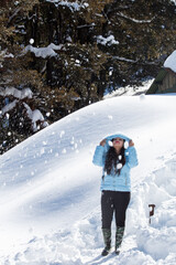 Woman wearing hooded winter coat and enjoying powder snow