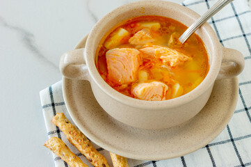 homemade soup with salmon with bread sticks on marble background.