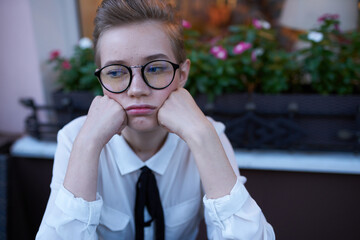 sad woman with short hair sits in a chair at the cafe table emotions model book