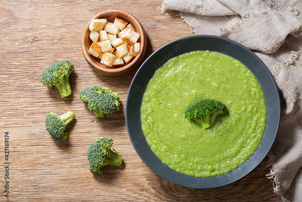 Wall mural plate of broccoli soup on a wooden background