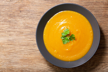plate of pumpkin soup with parsley on a wooden background