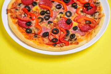 A whole, cooked and sliced peperoni pizza on a colorful backgroud, various colors. Copy space banner.