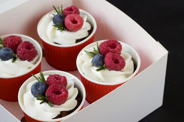 Dessert in a cups with cream cheese ,raspberries and blueberry in delivery box. Sweet food delivery