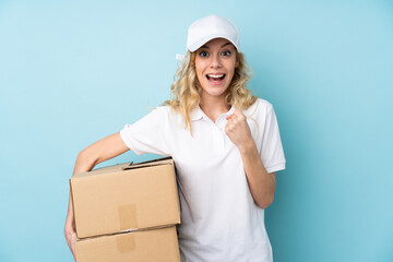 Young delivery woman isolated on blue background celebrating a victory