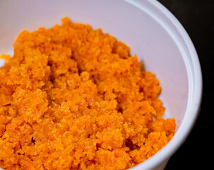 Close up of Carrot Halwa or Gajar ka halwa in a white takeout box on a black background.