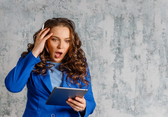 Stunned young woman shocked by unexpected news or message online on tablet. young European businesswoman.  woman feeling shocked after reading something on her tablet against