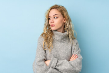 Young blonde woman wearing a sweater isolated on blue background portrait