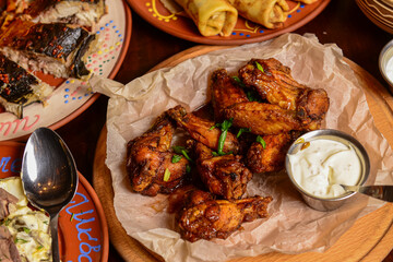 Chicken Wings with sauce served on a table for dinner. Whole meal, table covered with food.