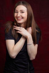 Fototapeta premium Portrait of a young woman with long brown hair, on a red textured background
