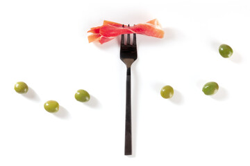 Ham on a fork with olives, shot from above on a white background